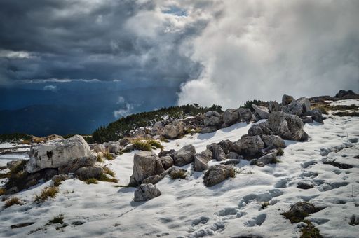on top of mountain Hohe Veitsch peak with stones and snow, view above the clouds, Styria, Austria