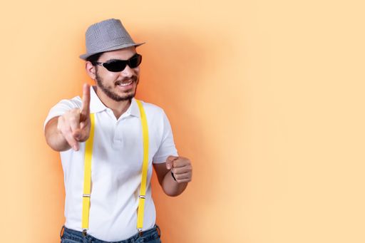 A hipster with beard and sunglasses, pointing at the camera and showing a sign of saying NO