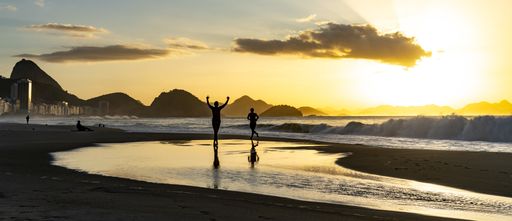 A breathtaking scene of two human silhouettes running along the beach