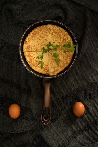 A vertical high angle closeup shot of an omelet divided into four pieces in a roaster and two eggs on the sides