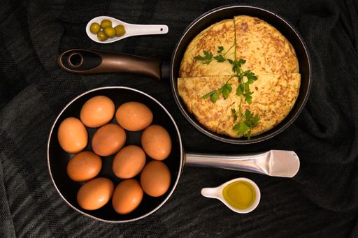A high angle closeup shot of two roasters in opposite directions with fresh eggs and an omelet with egg yolk and olives on the sides