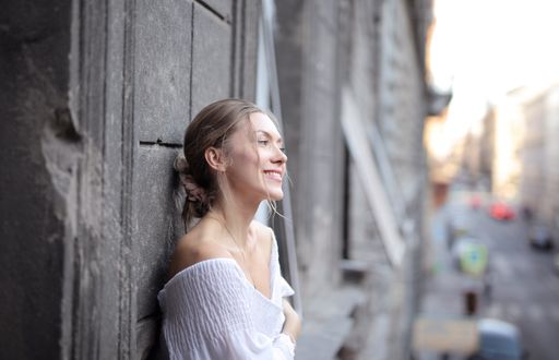 A young beautiful woman leaning on a wall and smiling