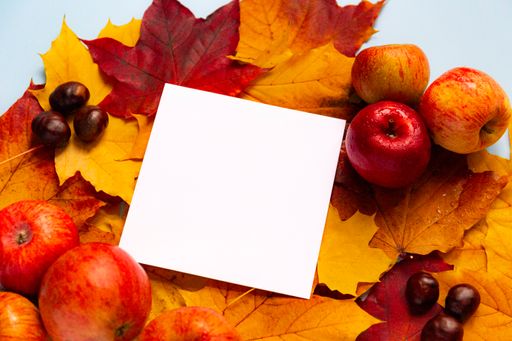 Beautiful autumn composition with apples, chestnuts, maple leaves, and paper for copy space.