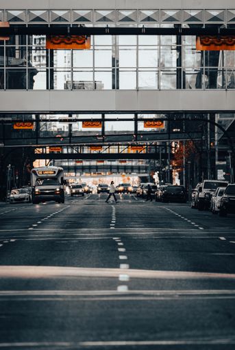 A vertical shot of a woman crossing the road with cars during heavy traffic in downtown Calgary