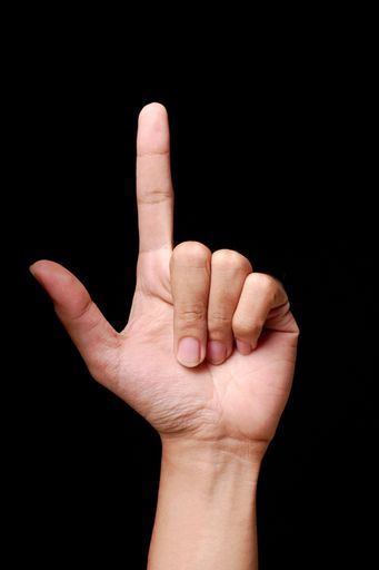 Hand showing the letter 'L' in sign language against a black background.