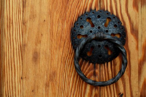A closeup shot of a vintage black door knocker on a wooden surface