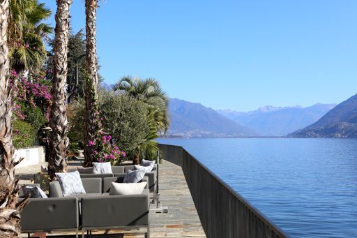 Relaxing lakefront terrace with palm trees and mountain view on Lake Maggiore, Switzerland.