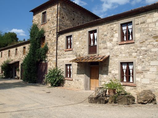 An old building with brick walls, windows and green bushes.