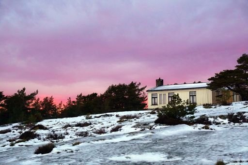The sunset sky over the winter field and a house