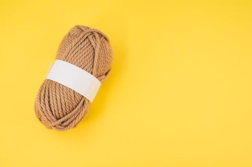 A vertical shot of isolated beige yarn on yellow background with text space
