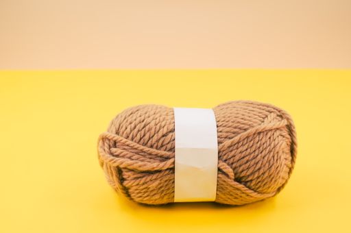 A vertical shot of isolated beige yarn on yellow background with text space