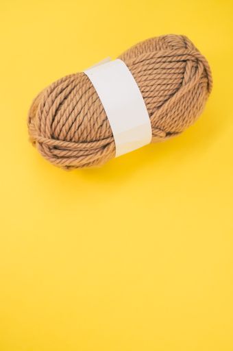 A vertical shot of isolated beige yarn on yellow background with text space