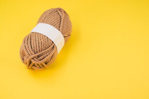 A vertical shot of isolated beige yarn on yellow background with text space