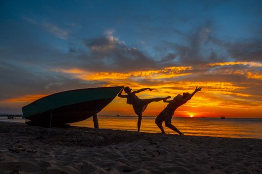 A beautiful silhouette of playing people next to the boat against a mesmerizing sunset in Roatan. Honduras