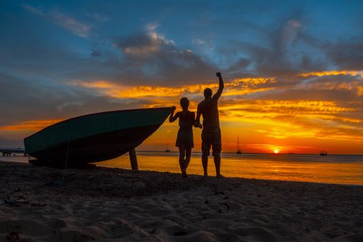 A beautiful picture of silhouettes standing next to the boat against a mesmerizing sunset in Roatan. Honduras