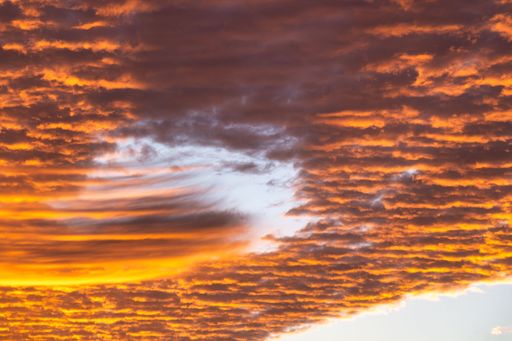 Vivid sunset sky with dramatic orange clouds and a hint of blue, creating a stunning natural scene.