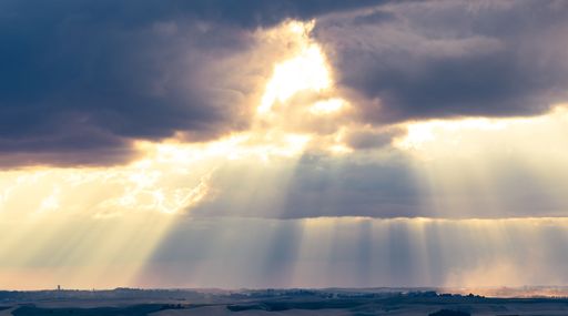 Sunbeams breaking through clouds over a scenic landscape, creating a dramatic and serene atmosphere.