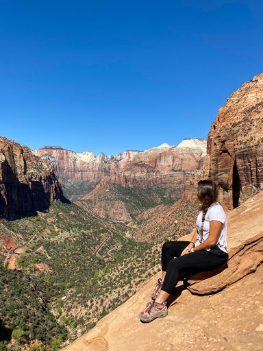 A vertical shot of a female sitting on the rock at the Zion National Park, Springdale, USA