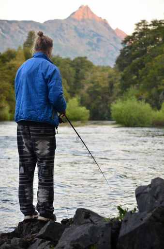 A back view of a male fishing on a lake shore in Nahuel Huapi national park, Argentina