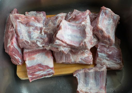 A top view of raw pork ribs on a wooden board in the kitchen sink