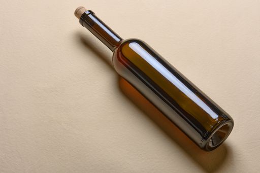 An empty wine bottle isolated on a beige background