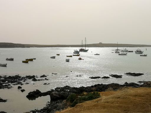 A beautiful view of small ships swimming near the rocky beach