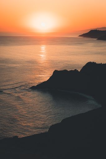A vertical shot of mountains and sea during the sunset