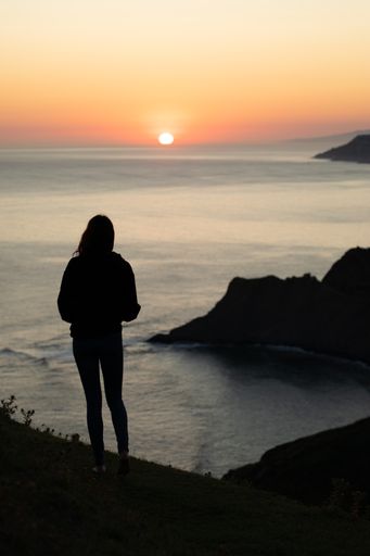 A vertical shot of a silhouette of a person standing on the hill