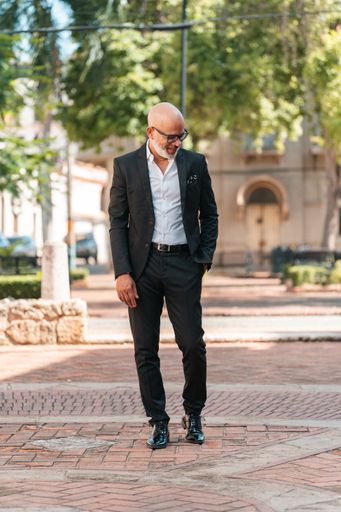 A vertical shot of a Hispanic male in an elegant suit posing on the street