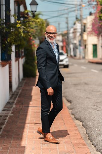 A vertical shot of a Hispanic male in an elegant suit posing on the street