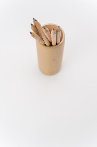 cylindrical pen holder made of solid wood on a white surface with text space with pencils