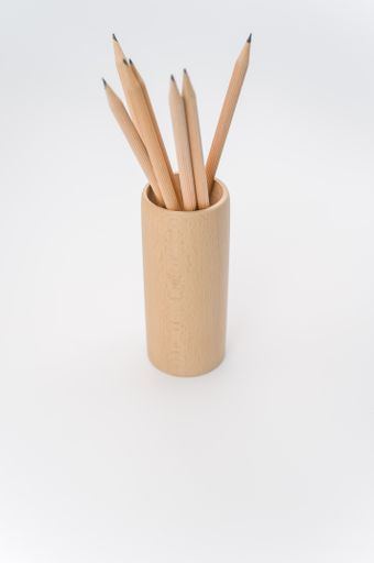 cylindrical pen holder made of solid wood on a white surface with text space with pencils
