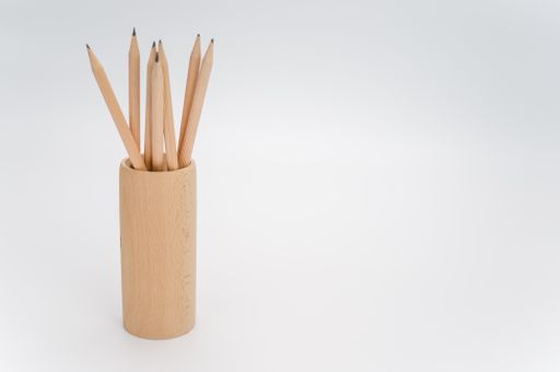 cylindrical pen holder made of solid wood on a white surface with text space with pencils
