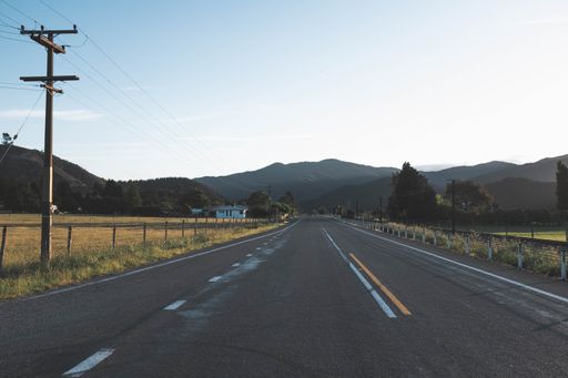 A beautiful shot of a gray empty lonely road in the countryside with mountains in the background