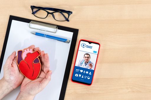 A top view shot of female hands holding heart, clipboard, glasses through a call with a doctor