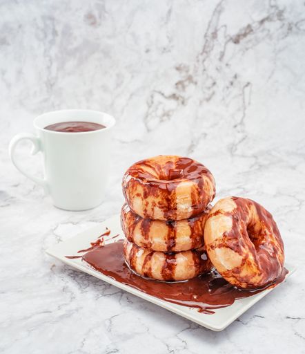 A closeup shot of delicious chocolate donuts and a cup of tea on the table