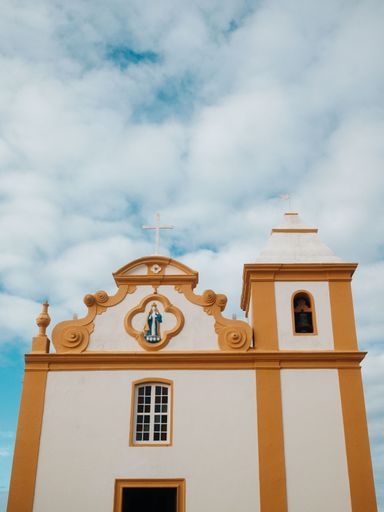 A picturesque church facade with ornate details under a partly cloudy sky, showcasing architectural beauty.