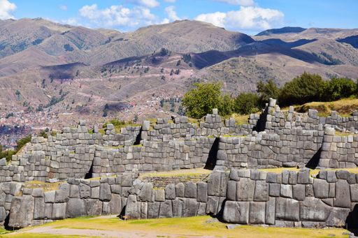 A vast stone fortress with interlocking walls against a backdrop of mountains.