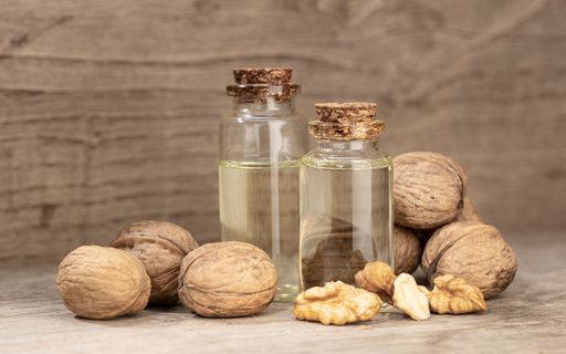Walnut oil still life. Glass bottle of nut oil on rustic wooden table