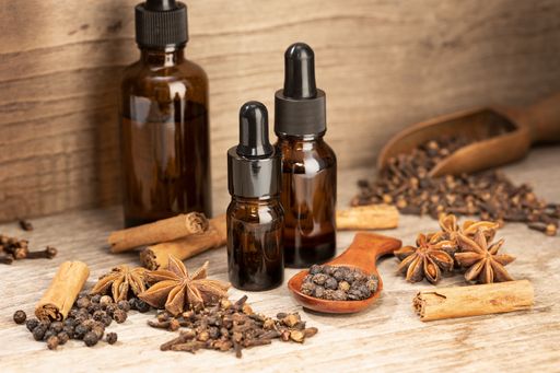Aromatic seeds essential oil still life. Amber glass bottle Cinnamon, anise, peppercorn, clove oil for wellness, spa, aromatherapy