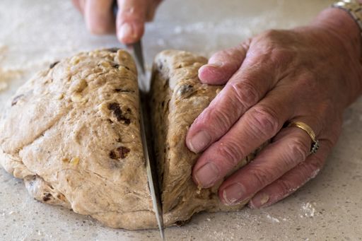 A closeup caption of a person making hot cross buns on Good Friday of Easter