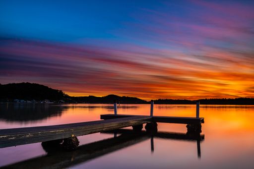 A wooden dock on the sea with long exposure during a breathtaking sunset in the evening