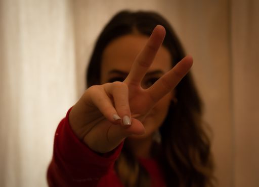 A portrait of a young brunette girl showing the peace sign at home