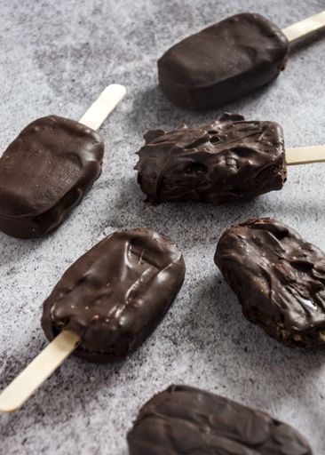 Chocolate-covered ice cream bars arranged on a textured surface, showcasing a delicious treat concept.