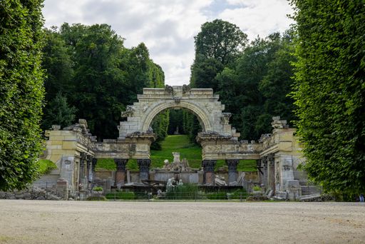 The fountains surrounded by greenery in Schonbrunn Garden under a cloudy sky in Vienna, Austria