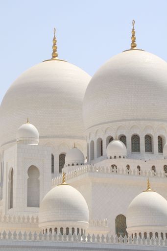 Close-up of Sheikh Zayed Grand Mosque's domes under a clear sky in Abu Dhabi, showcasing intricate Islamic architecture.