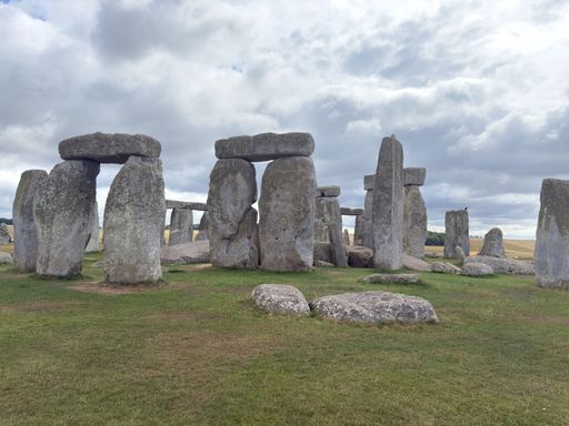 Stonehenge under a cloudy sky in Wiltshire, England, showcasing ancient stone structures on a grassy landscape.