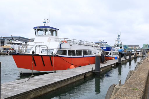 The docked boats at a marina featuring a vibrant red vessel in Poole
