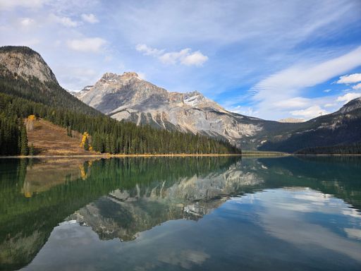Scenic view of a tranquil lake reflecting mountains under a blue sky in a serene natural setting.