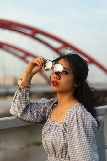 A vertical shot of an attractive young female with sunglasses under the sunlight in Saigon, Vietnam